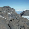 Blick von Osten (Stella Point) über den Kraterrand zum Uhuru Peak (Freiheitsgipfel), mit 5892 m der höchste Punkt Afrikas. Rechts die riesige Kluft (Krater-Aufbruch), wo Gletscher und Schmelzwasser austreten können. 